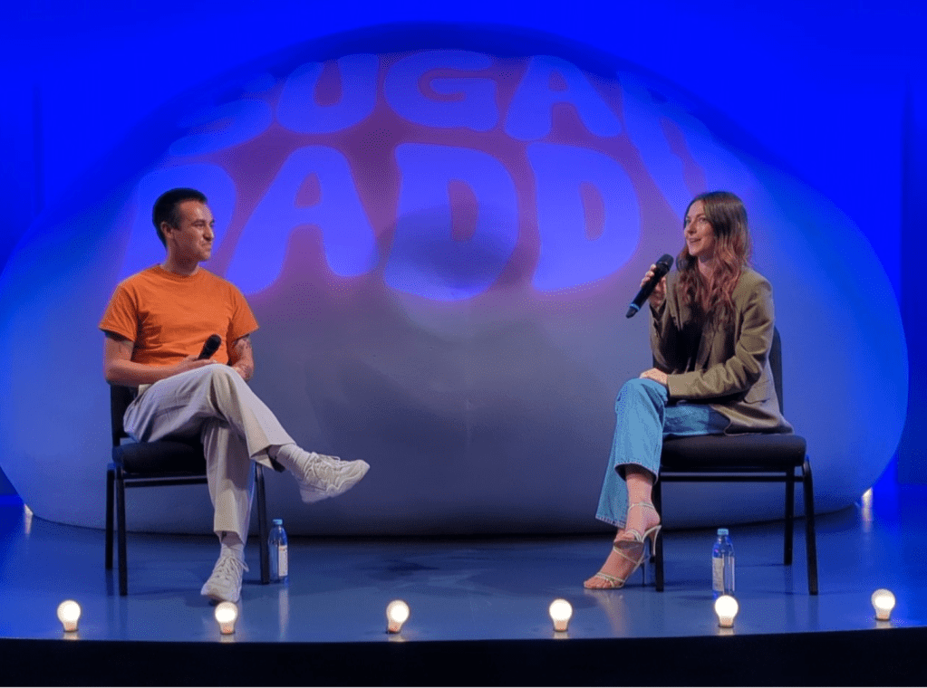 Two people sitting on stage talking.